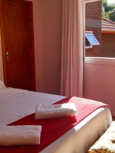a bedroom with a bed with a red blanket and a window at Recanto Ninho das Aguias in Nova Petrópolis
