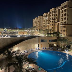 une piscine devant un hôtel la nuit dans l'établissement قريه اكوا فيو الساحل الشمالى-Aqua View North Coast, à El Qasaba esh Sharqīya