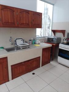 kuchnia z drewnianymi szafkami, zlewem i kuchenką w obiekcie 302 RV Apartments Iquitos-Apartamento familiar con terraza w mieście Iquitos