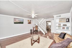 a living room with a ceiling fan and a staircase at Contemporary Master Queen Suite in Houston