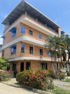 un gran edificio de ladrillo con una palmera delante de él en Apartamento acorde para una estadía tranquila., en Apartadó