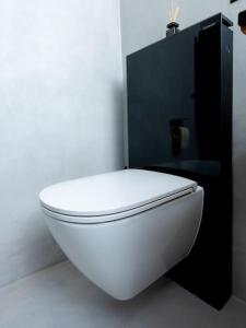 a white toilet in a bathroom with a black wall at Small but WOW! Studio with pool @ the central lake in Crans-Montana