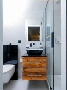 een badkamer met een wastafel, een toilet en een spiegel bij Small but WOW! Studio with pool @ the central lake in Crans-Montana