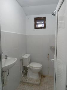 a white bathroom with a toilet and a sink at Bak Trieng Homestay - depan Mushalla Baitul Muttaqien BUPERTA in Lamnyong