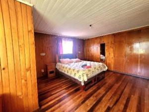 1 dormitorio con 1 cama en una habitación con suelo de madera en Eliodoro Yañez Casa o chalet, en Valdivia