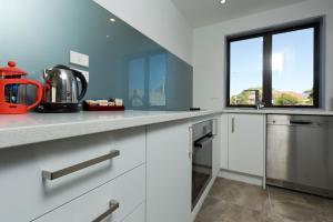 a kitchen with white cabinets and a window at 2 on Whiteleigh and 239 on Lincoln Motel in Christchurch