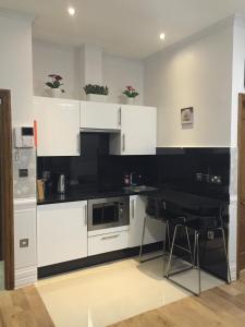 cocina con armarios blancos y encimera negra en Paddington Apartments, en Londres