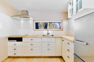 白马村Piccolo House的厨房配有白色橱柜、水槽和窗户