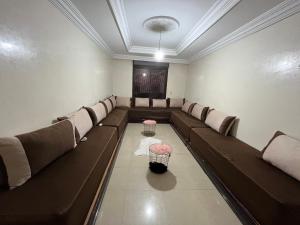 a waiting room with brown leather couches and a table at Residence Mly youssef appart in Safi
