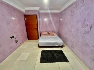 a bedroom with a bed in a purple wall at Residence Mly youssef appart in Safi