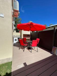 une table et des chaises avec un parasol rouge sur une terrasse dans l'établissement Casa para 4 personas en vista24uy, Bella Vista, Maldonado, à Bella Vista