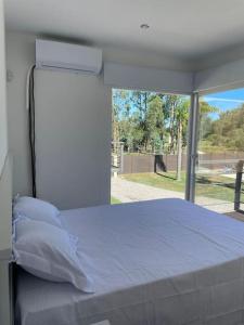 a bedroom with a white bed with a large window at Casa para 4 personas en vista24uy, Bella Vista, Maldonado in Bella Vista