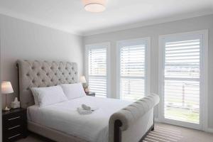 a white bedroom with a large bed and two windows at WineCountry Holiday House in Branxton