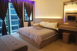 een slaapkamer met een bed met een tafel en een televisie bij NEW Cozy Studio - Trefoil Setia Alam in Shah Alam