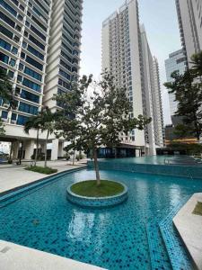 een boom in het midden van een zwembad met gebouwen bij NEW Cozy Studio - Trefoil Setia Alam in Shah Alam