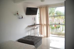 sala de estar con sofá, mesa y TV en Apartamento a 5 min da praia, en Florianópolis