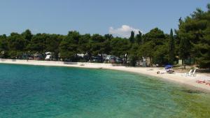 a beach with chairs and people sitting on the sand at Apartments Villa Magdalena in Trogir