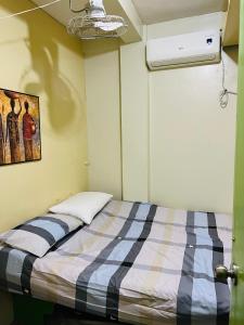 a bedroom with a bed with a blue and white blanket at RJ Apartment in Catbalogan