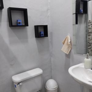 een badkamer met een toilet en een wastafel met twee foto's aan de muur bij Mini Suite totalmente amoblado recién reconstruido, camas muebles, bajilla, electrodomésticos totalmente nuevos Suit muy espaciosa, ideal para parejas o personas solas que viajan de trabajo in Cuenca