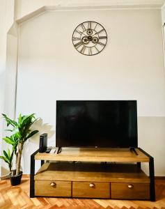 a flat screen tv on a tv stand in a living room with a clock at Madero Apartment in Buenos Aires