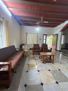 uma sala de estar com um sofá e mesas num piso de azulejo em The Coco Ranch em Chāmundi