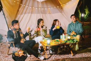 a group of people sitting around a table in a tent at Mộc Châu Island - Lune Camping in Mộc Châu
