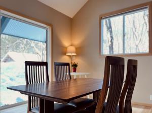 una sala da pranzo con tavolo in legno e 2 finestre di Piccolo House a Hakuba