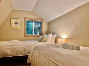 2 weiße Betten in einem Zimmer mit Fenster in der Unterkunft Piccolo House in Hakuba