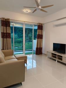 a living room with a couch and a flat screen tv at Nasuha Homestay in Sandakan
