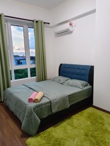 a bedroom with a bed with a blue headboard and a window at Nasuha Homestay in Sandakan