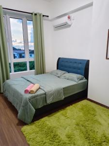 a bedroom with a bed with a green blanket and a window at Nasuha Homestay in Sandakan