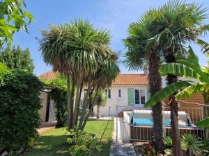uma villa com palmeiras e uma piscina em Maison Châtelaillon-Plage, 3 pièces, 4 personnes - FR-1-706-5 em Châtelaillon-Plage