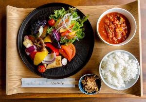 a black plate of food on a wooden tray with chopsticks at Always Niseko in Kutchan