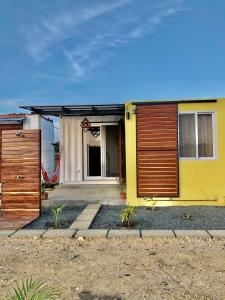 een geel huis met houten deuren in een tuin bij Low Tide - Popoyo Aparts in Popoyo