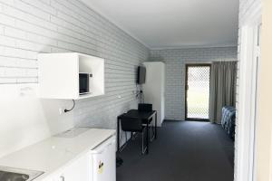 a kitchen with a desk and a bed in a room at Tocumwal Early Settlers Motel in Tocumwal