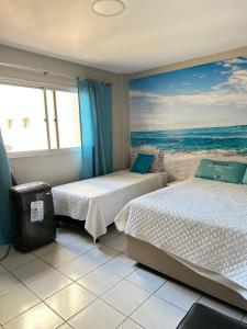 2 camas en una habitación con una pintura de la playa en Cobertura Duplex Beira Mar Praia do Morro, Guarapari, en Guarapari