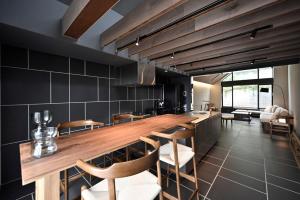 a kitchen with a long wooden counter and chairs at Kakurega Tokyo villa in Tokyo