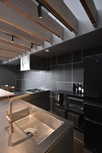 a kitchen with a stainless steel sink and black cabinets at Kakurega Tokyo villa in Tokyo