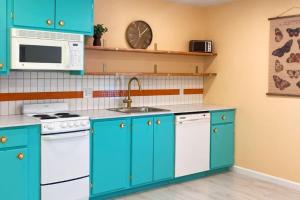 cocina con armarios azules, fregadero y microondas en The Bungalow, en Horseheads