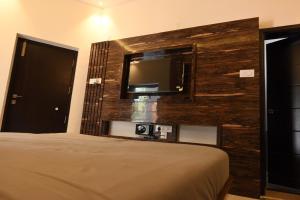 1 dormitorio con 1 cama y TV en la pared en Melody Inn en Yercaud