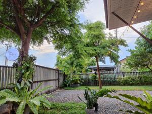 Ban Tha Nam Tun的住宿－Walai House วลัยเฮ้าส์ กาญจนบุรี，花园,花园内有栅栏,树木和植物