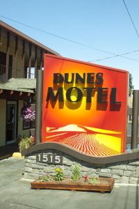 un cartel para un motel de dunas frente a un edificio en Dunes Motel - Bend, en Bend
