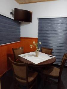a dining room with a table and chairs with a vase on it at Cabaña muy cómoda cerca de Saltos del Laja in Cabrero