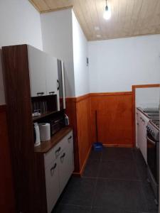 a small kitchen with white cabinets and a stove at Cabaña muy cómoda cerca de Saltos del Laja in Cabrero