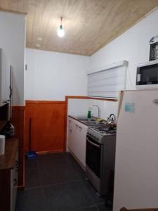 a small kitchen with a stove and a refrigerator at Cabaña muy cómoda cerca de Saltos del Laja in Cabrero