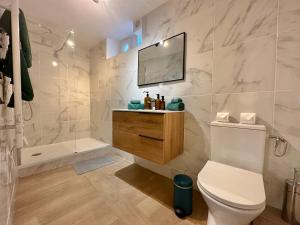 La salle de bains est pourvue de toilettes et d'une télévision murale. dans l'établissement Les Turquoises Étretat - L'Hôtel-Boutique, à Étretat