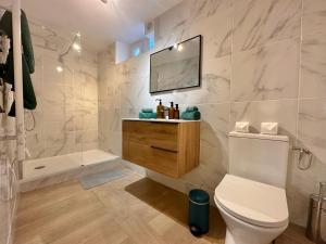 a bathroom with a toilet and a television on the wall at Les Turquoises Étretat - L'Hôtel-Boutique in Étretat