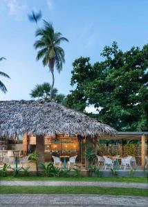 a hut with a straw roof with a palm tree at Palmera Eco Resorts Nilaveli in Trincomalee