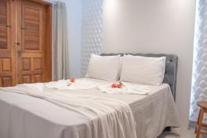 a bed with white sheets and red flowers on it at Apto a 300m da praia AxéMoi in Porto Seguro +13 photos