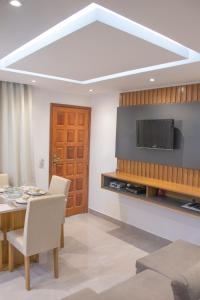 a living room with a television and a table and chairs at Apto a 300m da praia AxéMoi in Porto Seguro